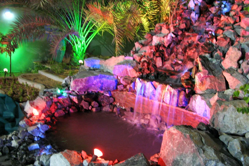 Koi Pond Maintenance in Dubai: Essential Summer Care for Extreme Heat 2 Colour-lit rock waterfall and pond at night