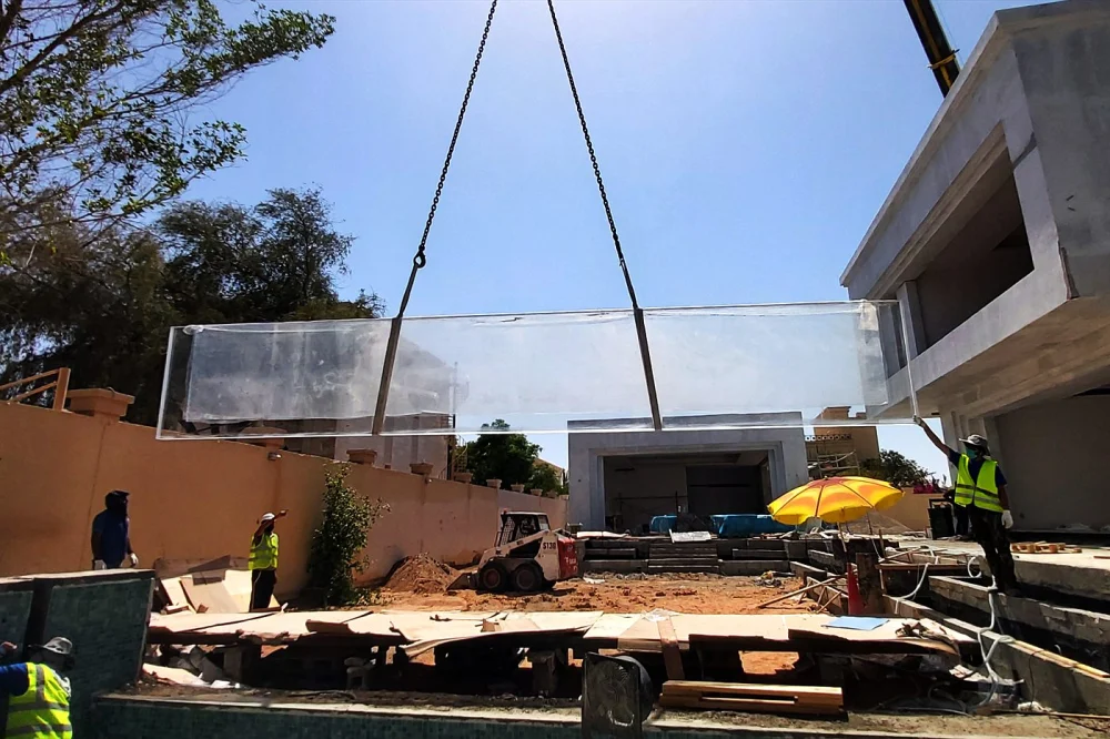 Swimming Pool Glass Panels in Dubai: Design Ideas, Safety, Costs & Installation Guide 2 Crane lifting a large acrylic pool panel on site