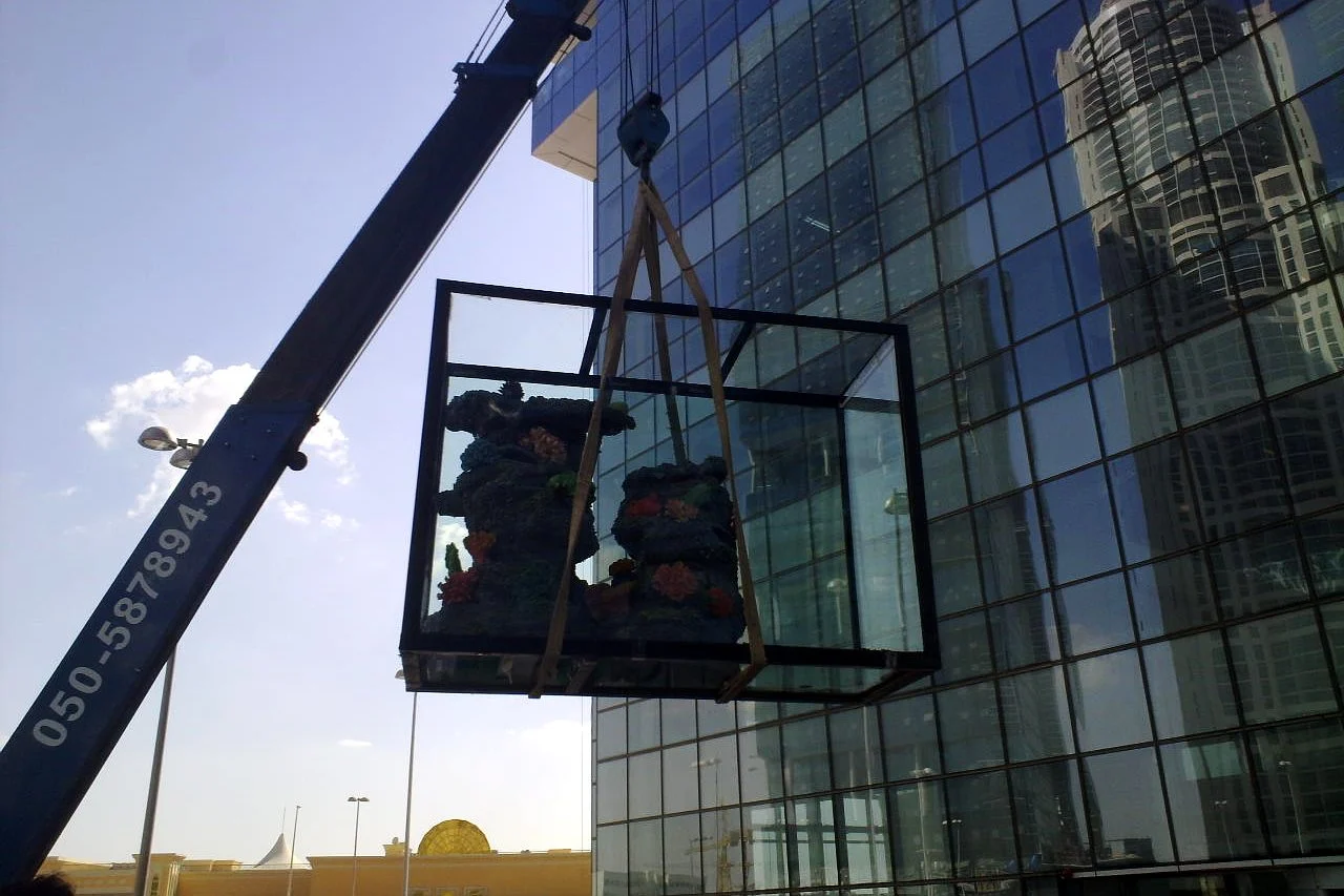 Crane lifting a large aquarium to an upper floor in Dubai