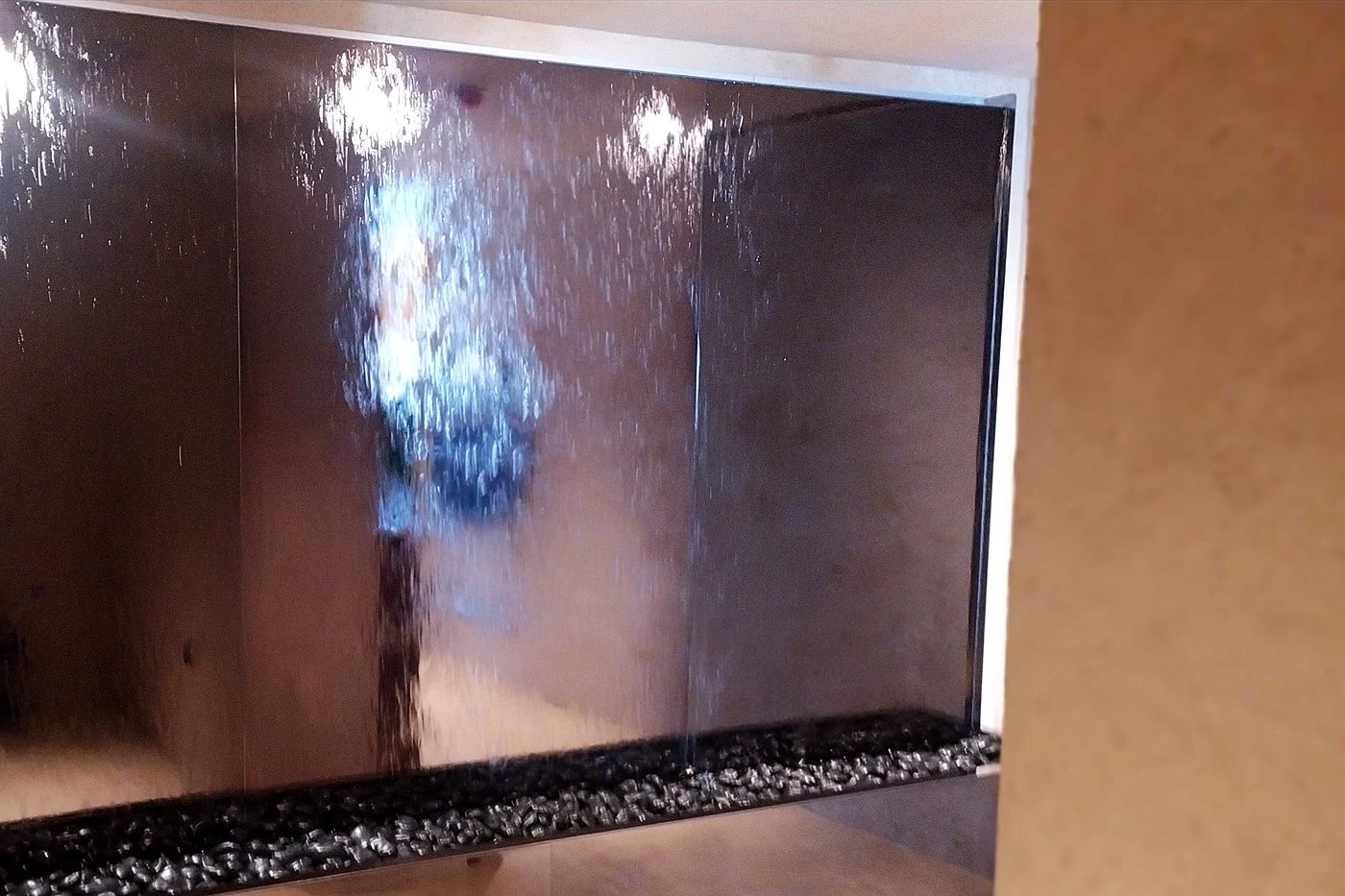 Indoor mirror water wall with a black pebble trough
