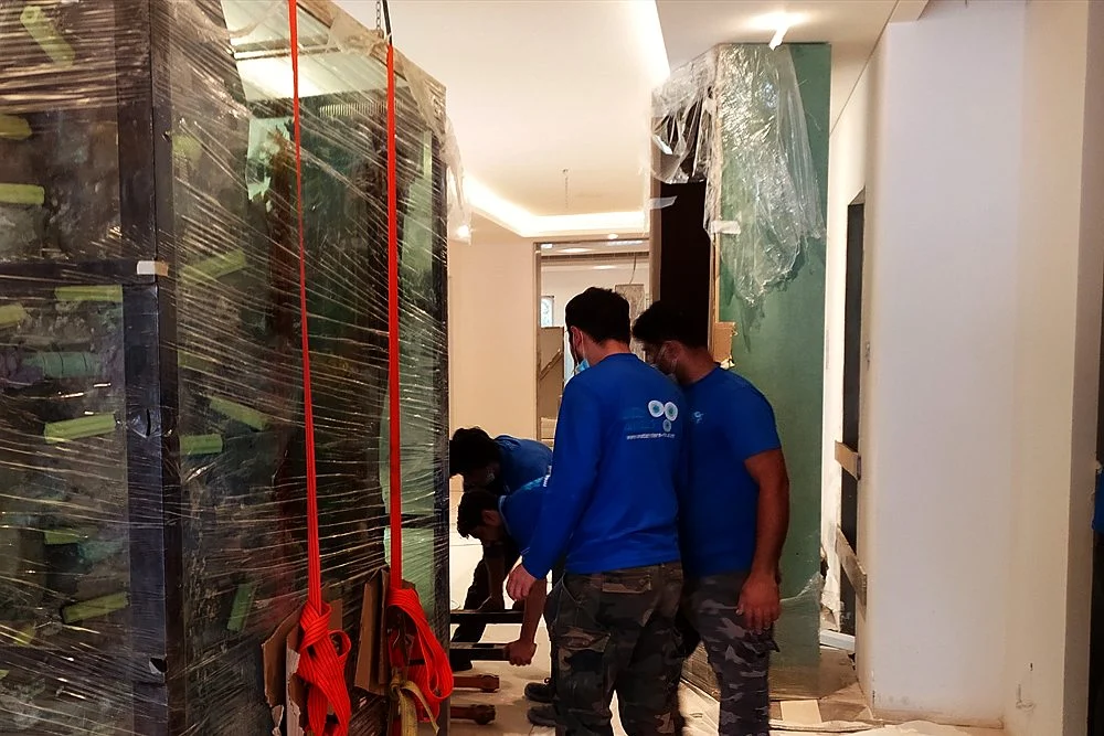 Aquarium Relocation in Dubai: How to Move a Tank Safely 1 Team moving a large glass aquarium panel into a building