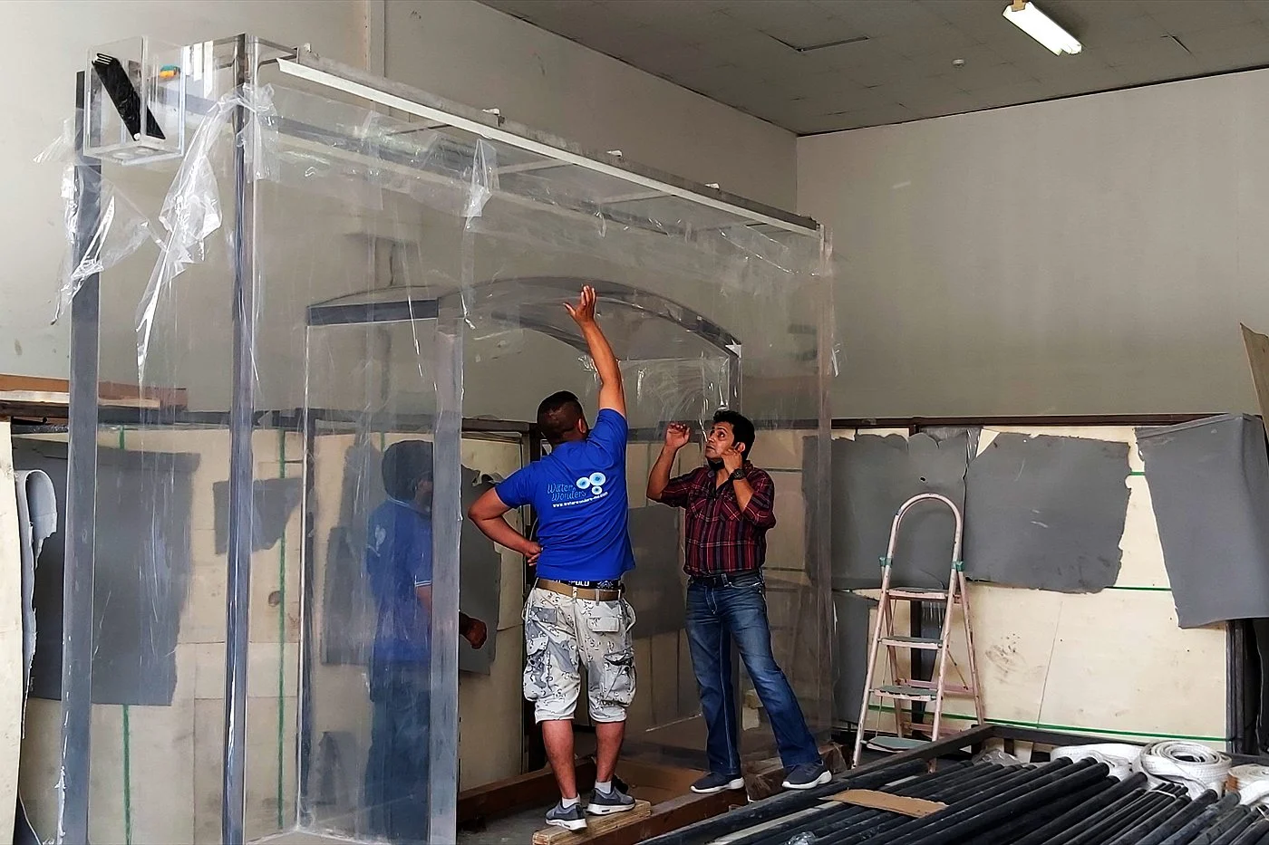 Technicians handling a large clear acrylic aquarium panel