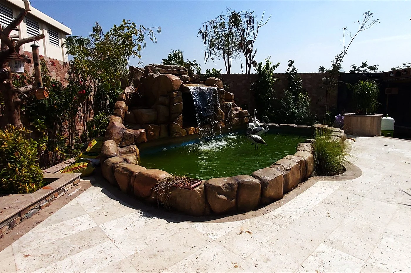 Villa garden pond with a rock waterfall and stone edging